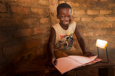 Child smiling while using a solar light to read
